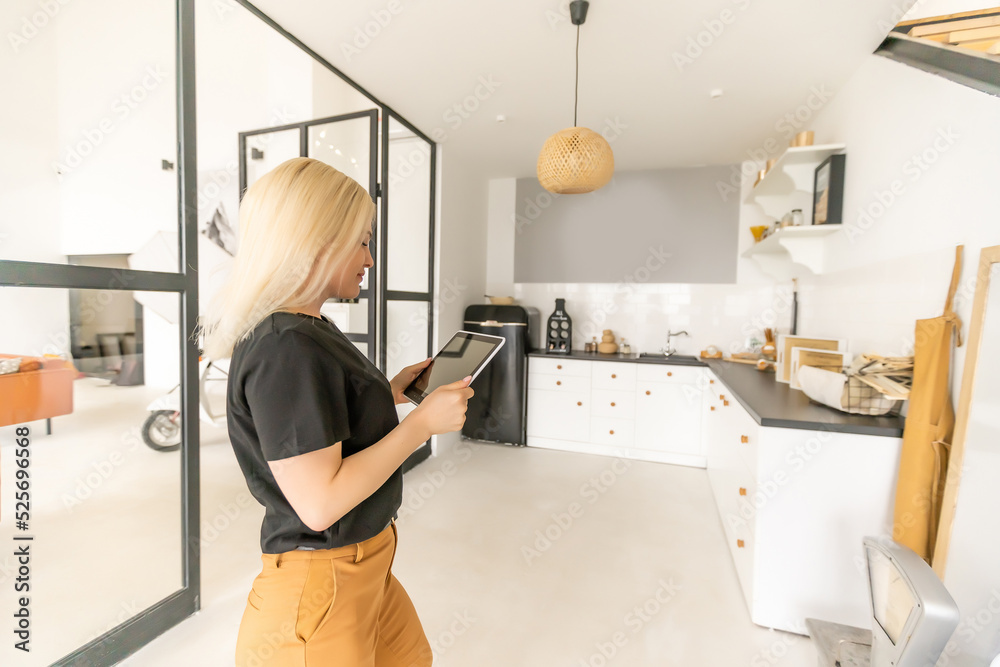 Woman use application for smart home control on tablet. Interior of living room in the background. Woman use application for smart home control on tablet. Interior of living room in the background.