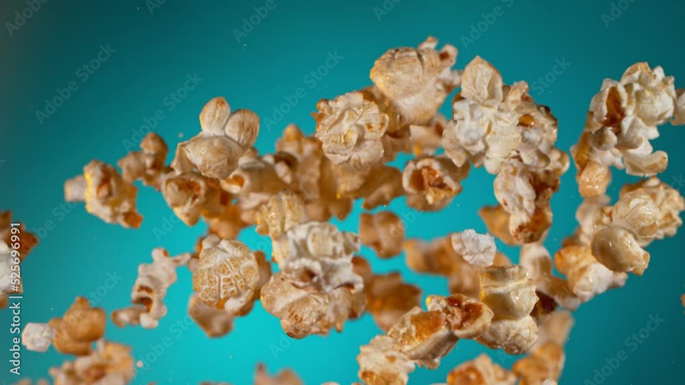 Super Slow Motion of Popcorn Flying on Gradient Blue Background. Filmed on High Speed Cinematic Camera at 1000 fps. Super Slow Motion of Popcorn Flying on Gradient Blue Background. Filmed on High Speed Cinematic Camera at 1000 fps.
