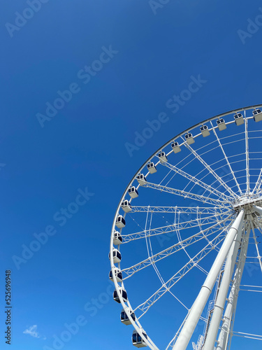 Grande roue sur un fond de ciel bleu dans le Vieux-Port de Montr  al. Cabines d un man  ge dans un parc d   amusement.