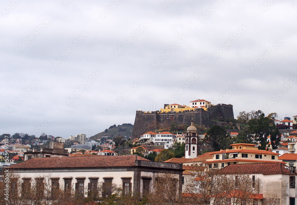 view of the city of funchal in madeira with the sao joao de pico hillside fortress in the distance