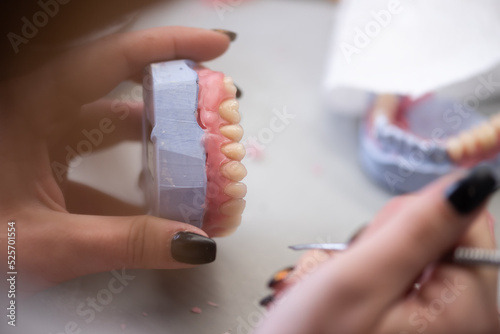 Prosthetics hands while working on the denture, false teeth, a study and a table with dental tools.