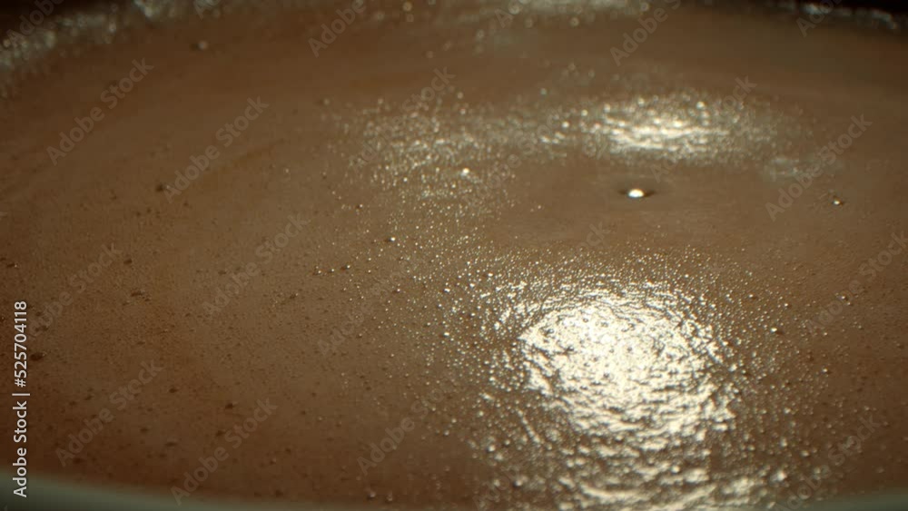 Close up shot cup coffee, side view from above of a mug with coffee the hand of a person stirs the foamy foam, stirring the coffee with a spoon. Close up shot cup coffee, side view from above of a mug with coffee the hand of a person stirs the foamy foam, stirring the coffee with a spoon.
