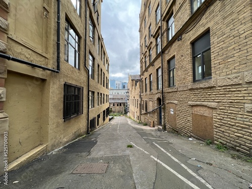 Fototapeta Naklejka Na Ścianę i Meble -  View down, Greenaire Place, with former Victorian warehouses, a derelict mill, and university buildings in the distance in, Bradford, UK