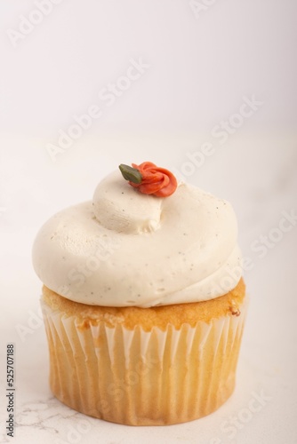 Close up of a vanilla cupcake with buttercream frosting and flower