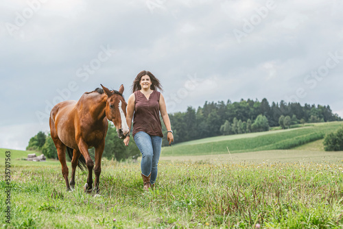 Portrait of a female equestrian interacting with her horse. A young woman cuddle with her brown horse