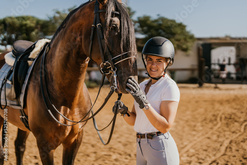 portrait of young woman in riding attire posing with horse before dressage with helmet © Samuel Perales