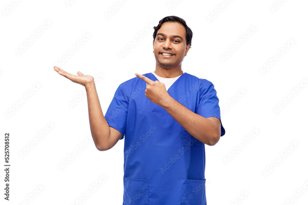 healthcare, profession and medicine concept - happy smiling indian doctor or male nurse in blue uniform holding something imaginary on empty hand over white background healthcare, profession and medicine concept - happy smiling indian doctor or male nurse in blue uniform holding something imaginary on empty hand over white background