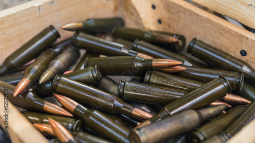 Numerous black rifle bullets with copper-coloured endings placed in a wooden box. Closeup shot. Military. Gun range concept. High quality photo