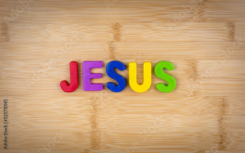 The word jesus is laid out of multicolored letters on a table background with a wood texture. Concept. Faith. Jesus