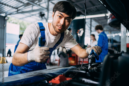 Auto handsome mechanic repairman smile in uniform standing thumbs up in the garage, positive thinking, repair and maintenance service concept.