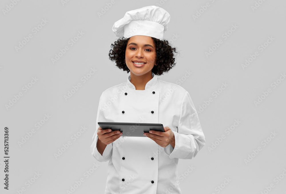 cooking, culinary and people concept - happy smiling female chef in toque and jacket with tablet pc computer over grey background cooking, culinary and people concept - happy smiling female chef in toque and jacket with tablet pc computer over grey background