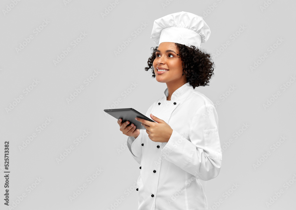 cooking, culinary and people concept - happy smiling female chef in toque and jacket with tablet pc computer over grey background cooking, culinary and people concept - happy smiling female chef in toque and jacket with tablet pc computer over grey background