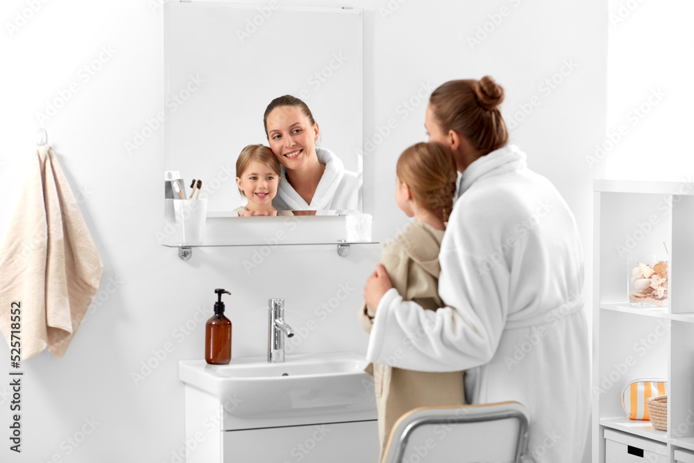 beauty, hygiene, morning and people concept - happy smiling mother and daughter looking to mirror in bathroom beauty, hygiene, morning and people concept - happy smiling mother and daughter looking to mirror in bathroom