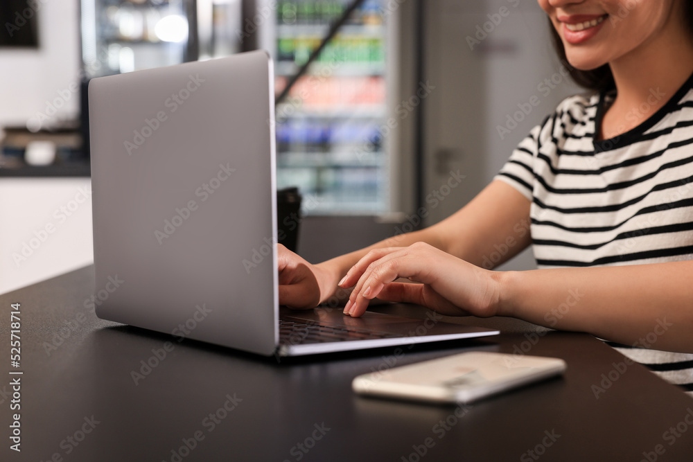 Happy young woman using laptop at table in hostel dining room, closeup Happy young woman using laptop at table in hostel dining room, closeup