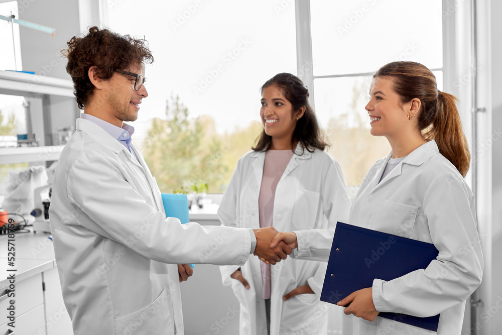 science, work and people concept - international group of happy scientists shaking hands in laboratory science, work and people concept - international group of happy scientists shaking hands in laboratory
