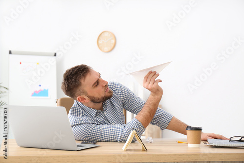 Canvas Print Lazy office employee playing with paper plane at workplace