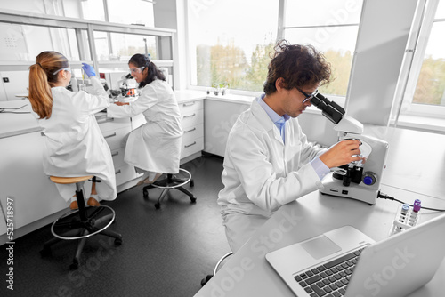 science research  work and people concept - international team of scientists with microscopes working in laboratory