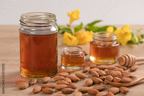 Honey jar with almonds honey dipper on wooden table