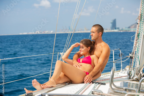 Young woman and man enjoying warm summer day during romantic sea travel along shoreline of Spain on modern yacht.. © JackF