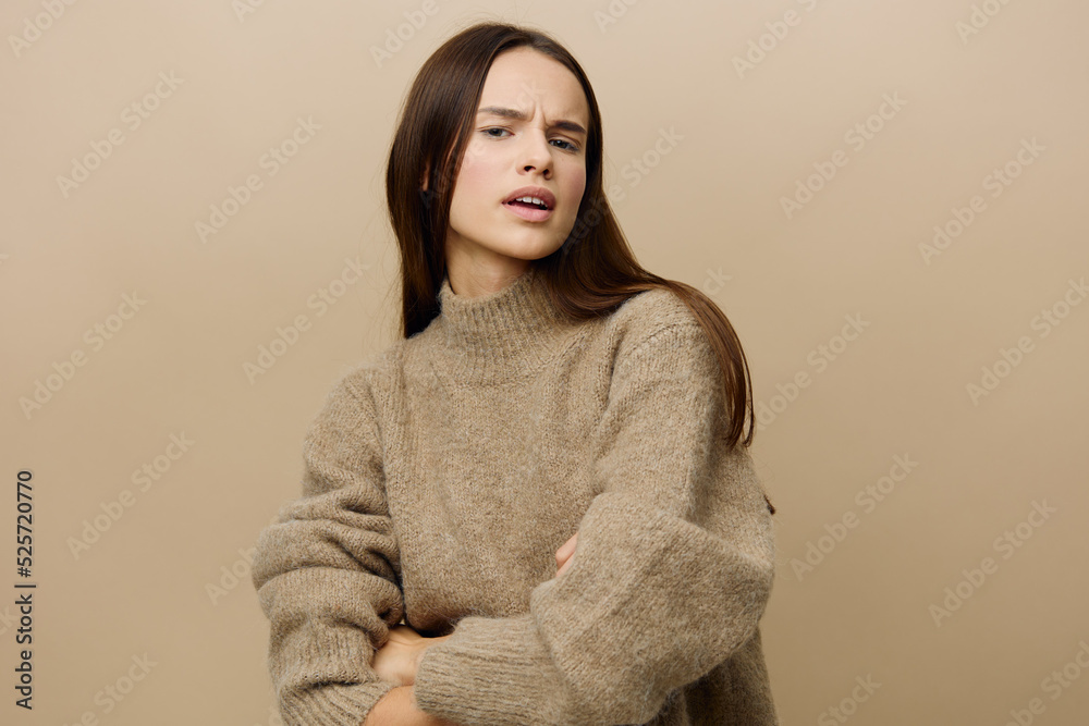 Fototapeta premium a relaxed, slightly upset woman stands in a stylish textured sweater, arms crossed over her chest and looks at the camera