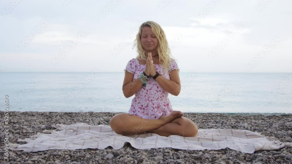 Woman in summer dress meditating by the sea Woman in summer dress meditating by the sea