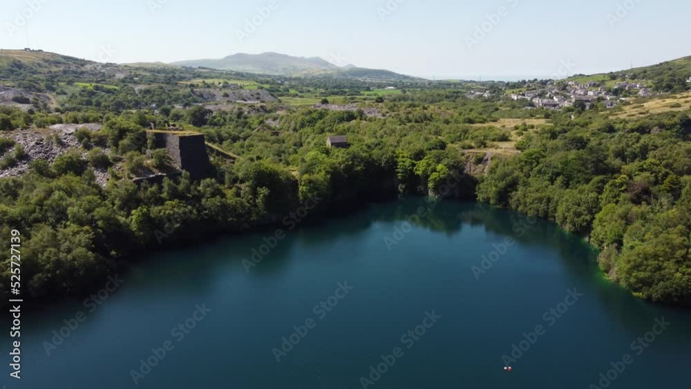 Aerial view Welsh woodland valley slate mining shaft and Snowdonia mountains descent towards quarry lake Aerial view Welsh woodland valley slate mining shaft and Snowdonia mountains descent towards quarry lake