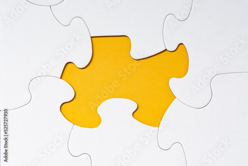 White jigsaw puzzle with some missing pieces on yellow background.