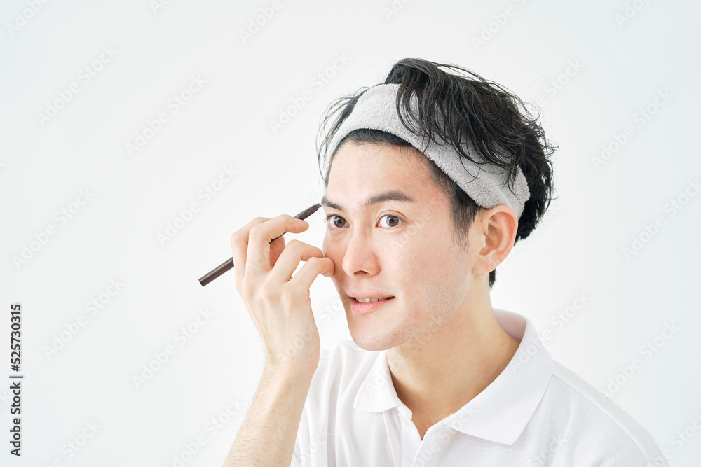 Obraz premium 白背景でアイブロウペンシルで眉毛を描く男性