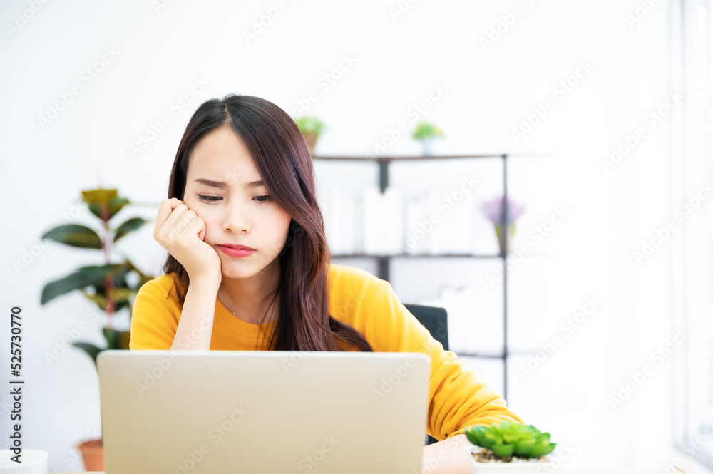 Asian young woman seriously working on computer laptop in house. She thinking find solution problem of work Asian young woman seriously working on computer laptop in house. She thinking find solution problem of work