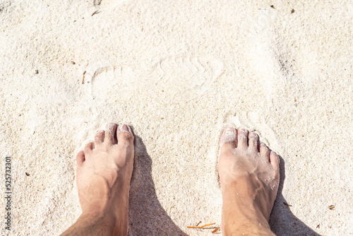 2 feet on the bleach. Close up of young man feet on a tropical sandy beach.