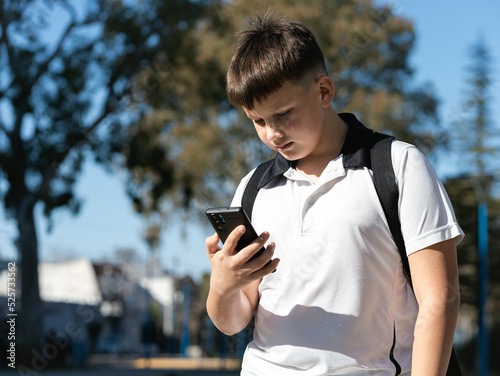 Schoolboy looking at the phone outdoors photo