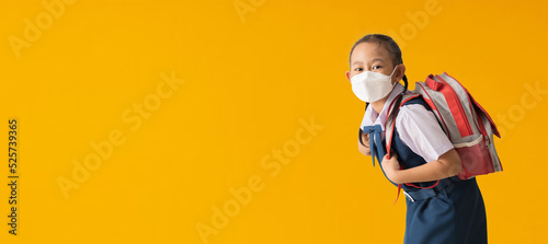 Asian schoolgirl in uniform wear medical face mask, isolated on yellow background with Clipping paths for design work empty free space
