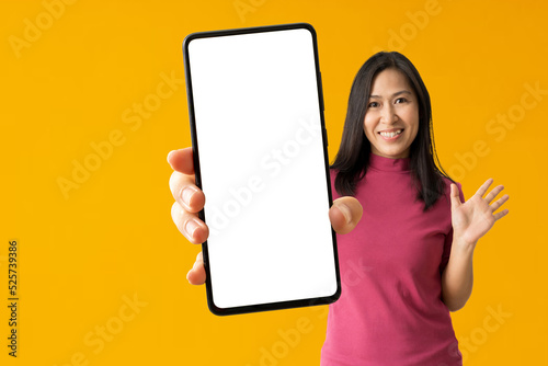 Happy asian woman holding big smartphone on yellow background, isolated Clipping paths for design work empty free space mock up product display presentation. © kromkrathog