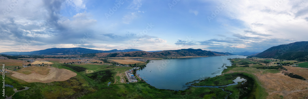 Aerial View of Okanagan Lake with farm lands and mountain landscape. Cloudy Sunset Sky. Near Vernon, British Columbia, Canada. Nature Panorama Background