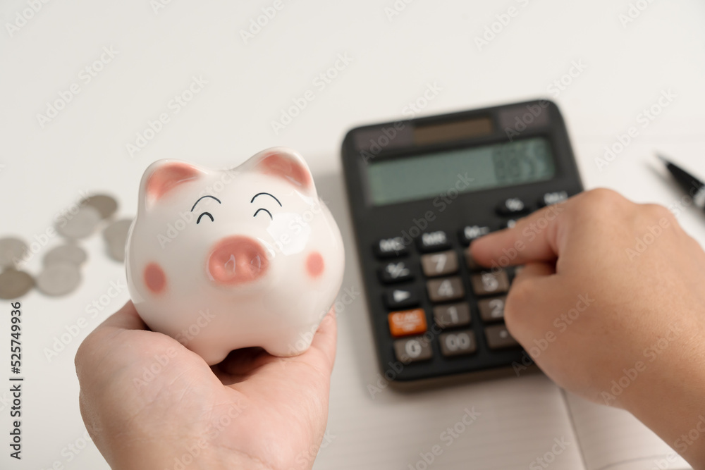 Woman save money in piggy bank and calculating for household expense Woman save money in piggy bank and calculating for household expense