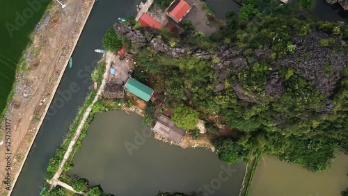 A descending aerial shot of property on a canal in Tam Coc, South East Asia, reveals a group of small boats. photo