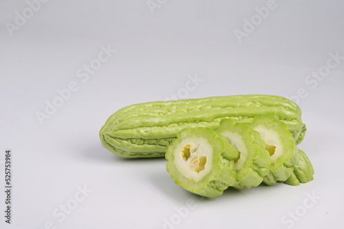 Organic Bitter melon or fresh Momordica charantia with cut slice on white background. (Scientific name: Momordica charantia L.). 1 bitter gourd cut into four pieces and 1 bitter gourd not cut 
