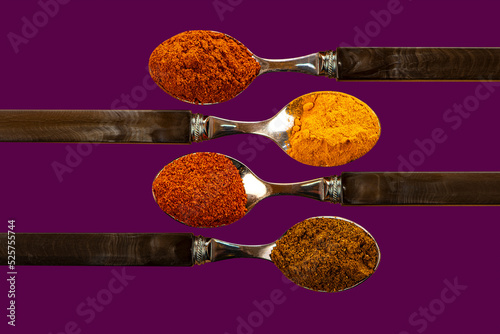 A selection of cayenne pepper tumeric chilli curry powder spices used in Indian cooking on a coulerful purple background photo