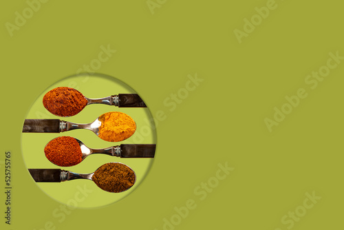 A selection of cayenne pepper tumeric chilli curry powder spices used in Indian cooking on a coulerful green background photo