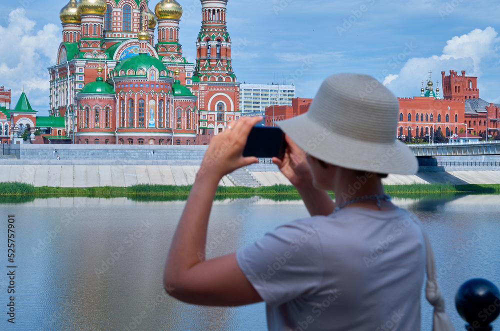 Fototapeta premium Woman tourist in a straw hat makes a mobile photo on a city street