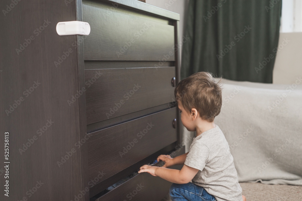 Child unsupervised plays with cabinets. Danger for the baby to pinch the hand of the cabinet door. Protect children from home furniture kids safety. Selected focus Child unsupervised plays with cabinets. Danger for the baby to pinch the hand of the cabinet door. Protect children from home furniture kids safety. Selected focus