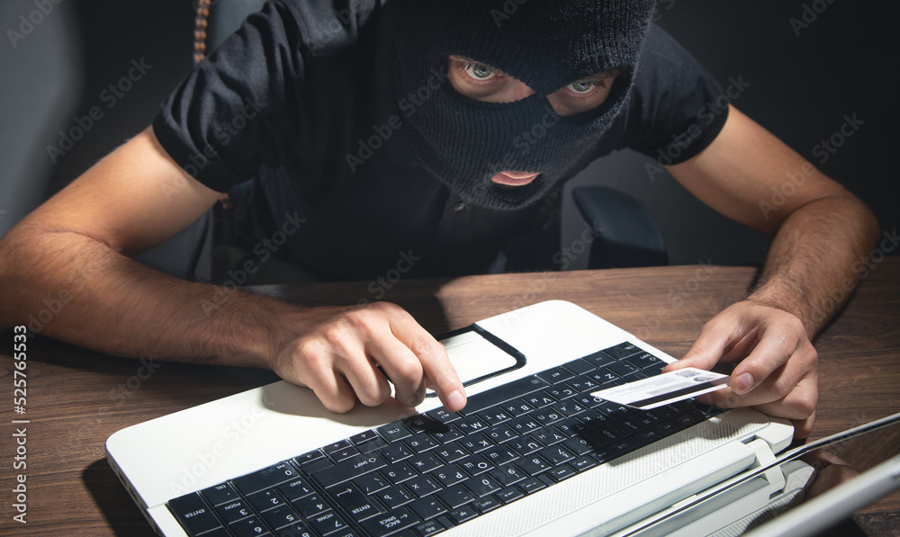 Hacker with credit card and laptop computer. Cyber crime Hacker with credit card and laptop computer. Cyber crime