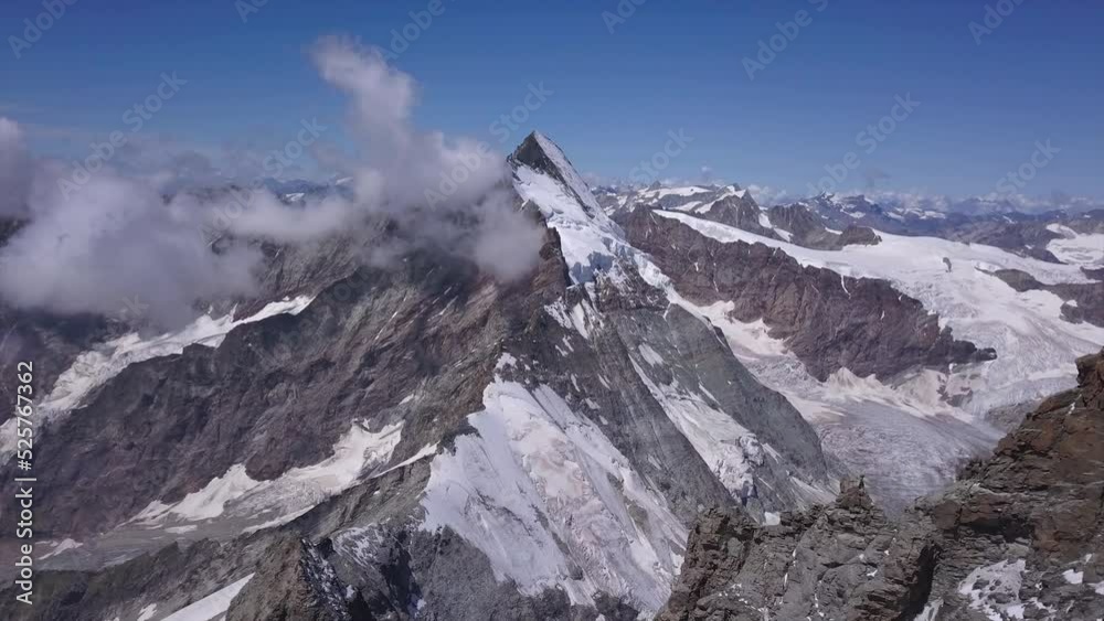 Stunning aerial view of The Matterhorn, Mount Cervino, Mont Cervin and surrounding mountains and valleys of the Alps. Drone flying forward. Mountain climbing dream destination landmark location. Stunning aerial view of The Matterhorn, Mount Cervino, Mont Cervin and surrounding mountains and valleys of the Alps. Drone flying forward. Mountain climbing dream destination landmark location.