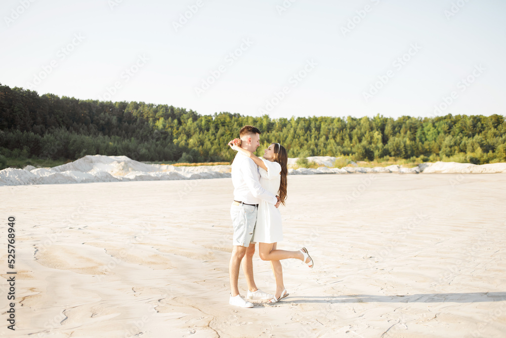 Young couple hugging on a sandy beach on a sunny day