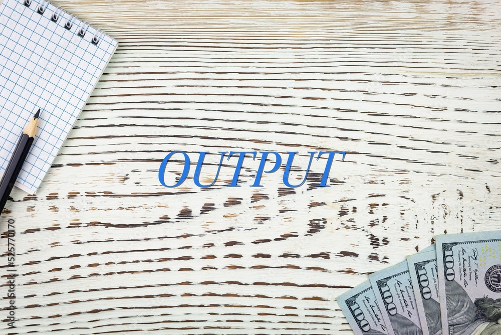Naklejka premium OUTPUT - word (text) and dollars on a white wooden table, notebook, notepad. Business concept: buying, selling, commerce (copy space).