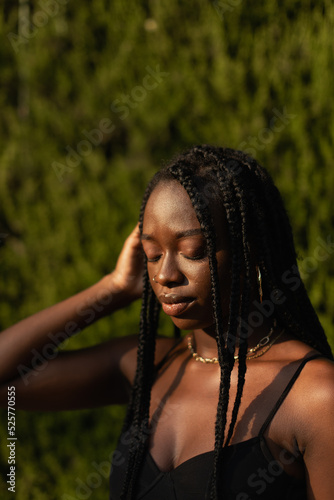 Portrait of a young black female removing her hair from her face whit her eyes closed during a sunset modeling session