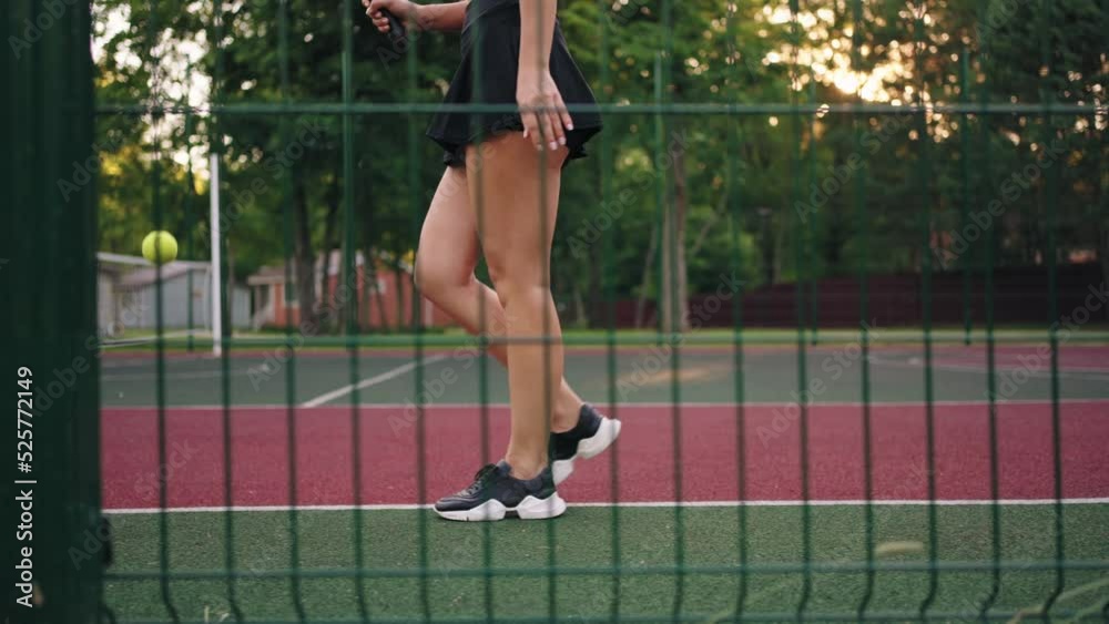 sporty woman is walking on tennis court and bouncing ball, view on her slender legs, female tennis player sporty woman is walking on tennis court and bouncing ball, view on her slender legs, female tennis player