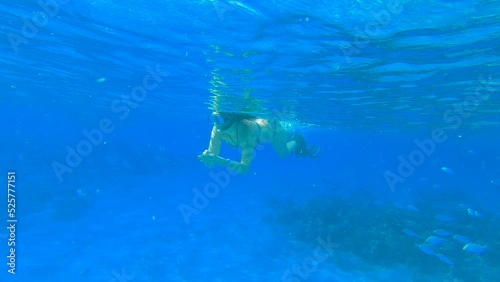 Woman in fins swimming on the surface of the sea - slow motion. Female snorkeler swims underwater and looking on underwater world
