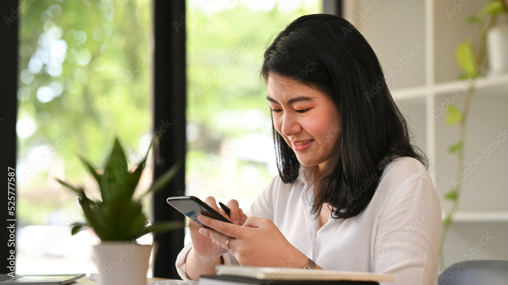 Pleasant asian woman chatting online, typing text message on her smart phone Pleasant asian woman chatting online, typing text message on her smart phone
