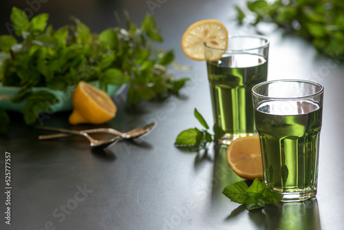 Lemon mint iced green tea cocktail refreshing drink for summer days two glass herbal dark background.